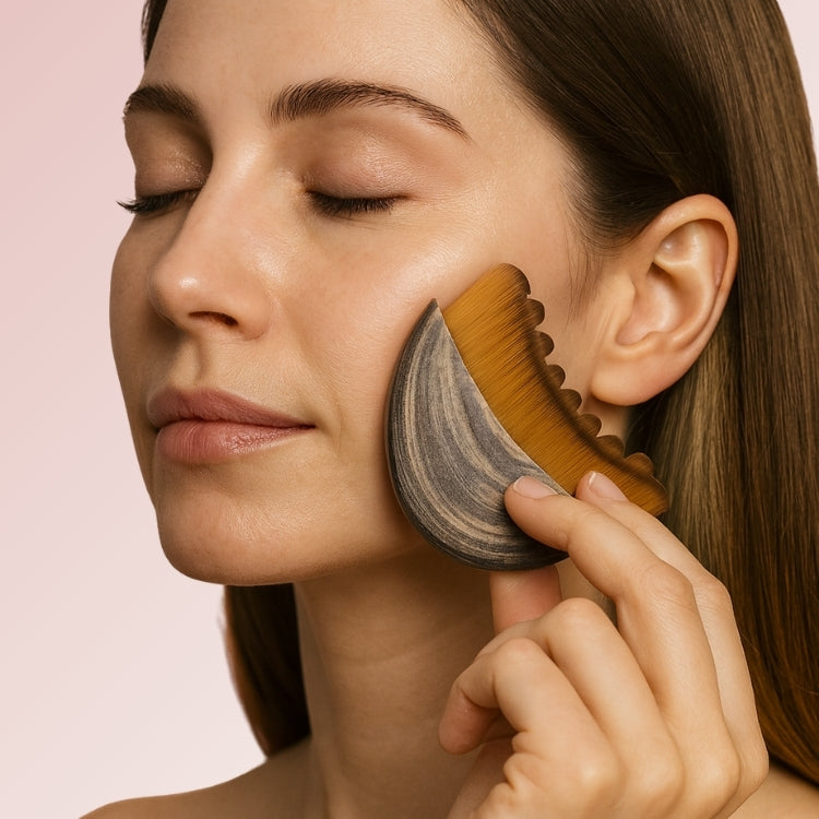 Woman using Clara Contour's lymphatic drainage brush on her face with a pink backdrop.